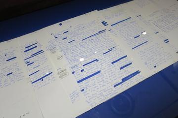 Image of Roland Barthe's notebooks in a glass display case. Blue text on white paper against a blue background.