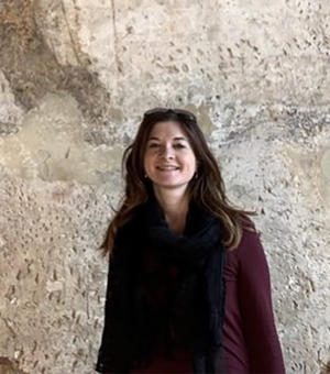 Photo of Emanuela Vai smiling to camera with rocky surface behind
