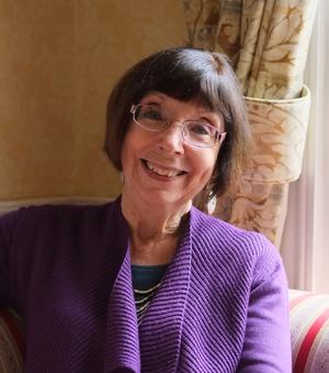 Photo of Susan Doran smiling to camera, sitting on a sofa.