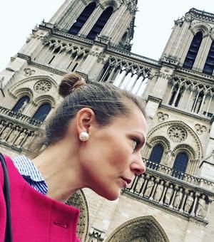 Headshot of Leah Clark in profile in front of Notre Dame in Paris. 