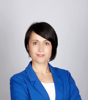 Photo of Diana Berruezo Sanchez looking to camera with her arms folded, standing in front of a white background.